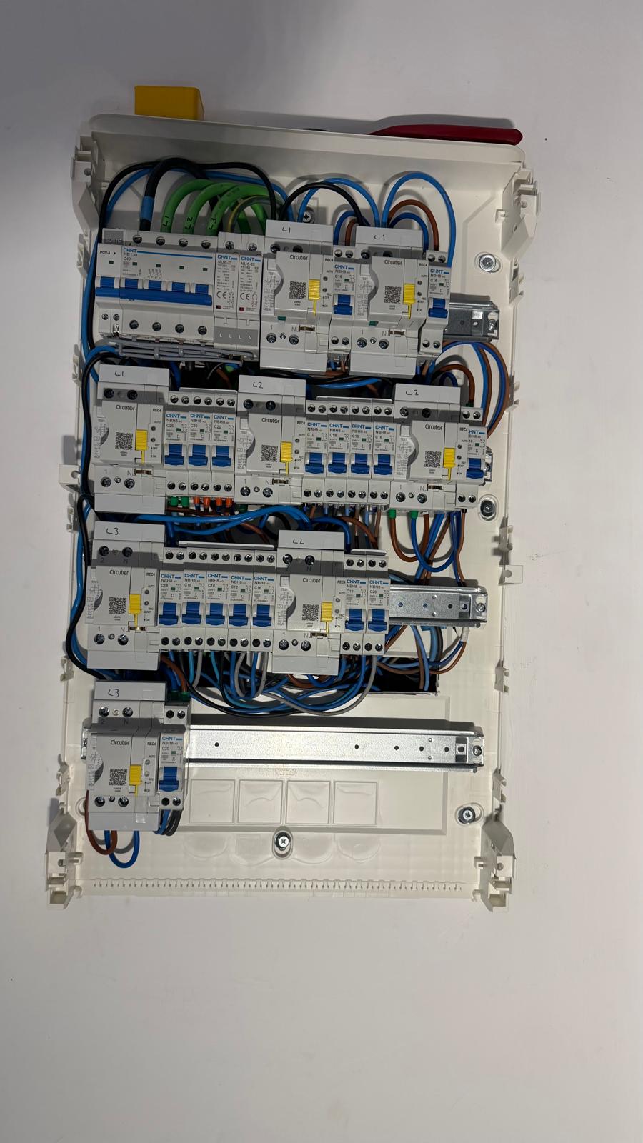 Close-up of the populated rails — every one of the eight Circutor REC4 self-reclosing RCDs is identifiable by its yellow service handle and Circutor branding, sat on the same DIN rail as the Chint NB1 1P+N (double-pole, single-element) MCBs and balanced across the L1, L2 and L3 phase labels printed on the chassis. This brand interoperability is exactly the point: Chint and Circutor modules share the same standard 18 mm-per-module DIN-rail pitch — each Circutor REC4 RCD occupies two module slots and each Chint NB1 1P+N MCB occupies two slots as well — and combine cleanly in a single coherent enclosure.