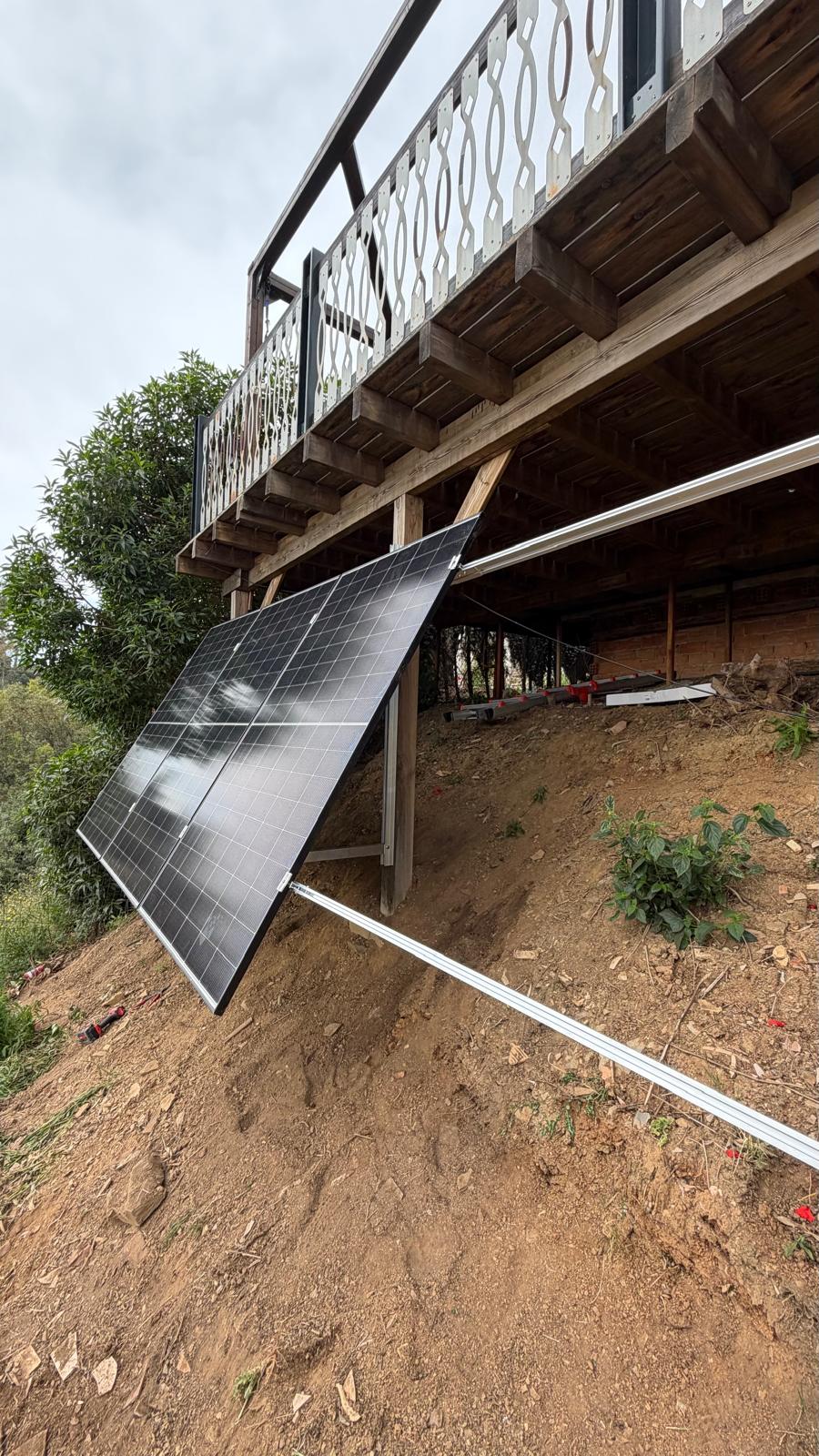 Primer panel mono PERC de 500 W sujeto a las correas — el panel se apoya en el carril de aluminio inferior y se sujeta arriba y abajo con grapas intermedias y finales PV estándar en inoxidable A2. Montar un único panel permite al ingeniero verificar la geometría panel-carril, el plan de gestión de cableado y la separación entre el dorso del panel y la estructura de acero (>50 mm para circulación de aire y para mantener baja la temperatura de célula del panel en las tardes de verano) antes de subir el resto del string.