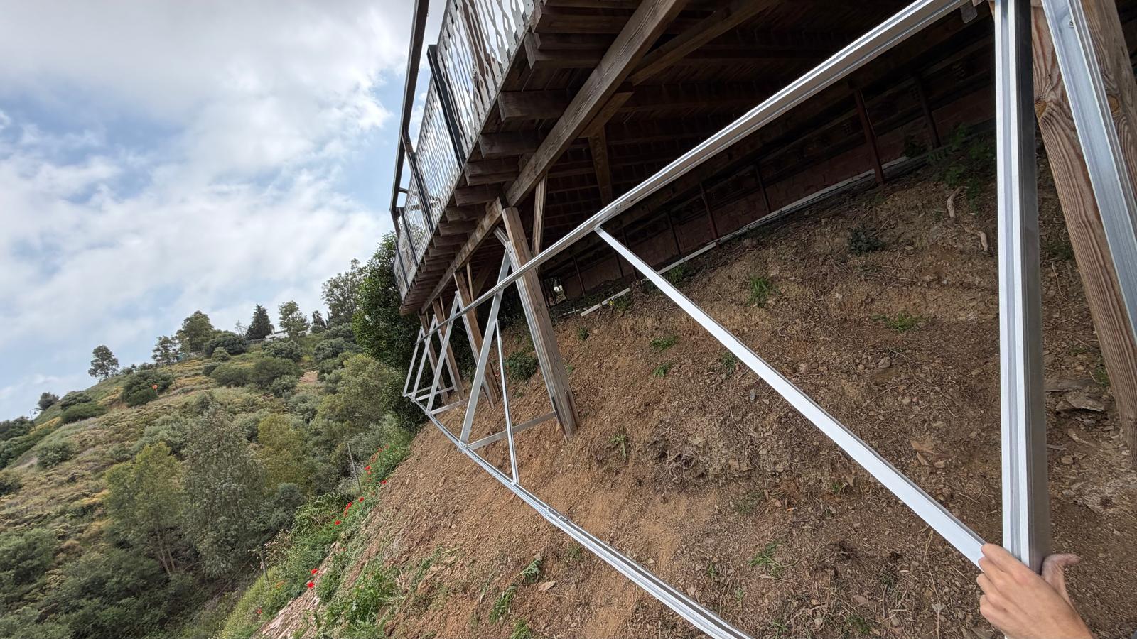Instalación de la estructura en curso — operario montando uno de los elementos diagonales inferiores. La estructura se atornilla en obra, no se suelda: cada elemento se fabrica, se perfora y se galvaniza en caliente en el taller, y luego se ensambla con tornillería inoxidable A2 en obra. Soldar en obra quemaría el recubrimiento de zinc y crearía puntos de inicio de corrosión; el ensamblaje atornillado preserva la integridad de la galvanización en cada unión.