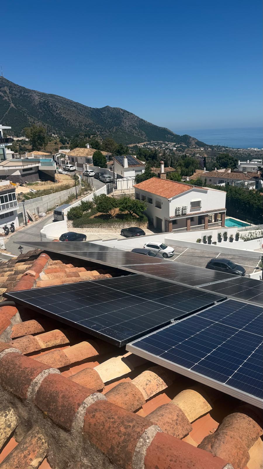Vista final de la reinstalación completada — paneles en dos filas sobre el sistema de raíles de aluminio, correctamente sujetos y asegurados. La Sierra de Mijas proporciona el fondo con el Mediterráneo visible más allá.