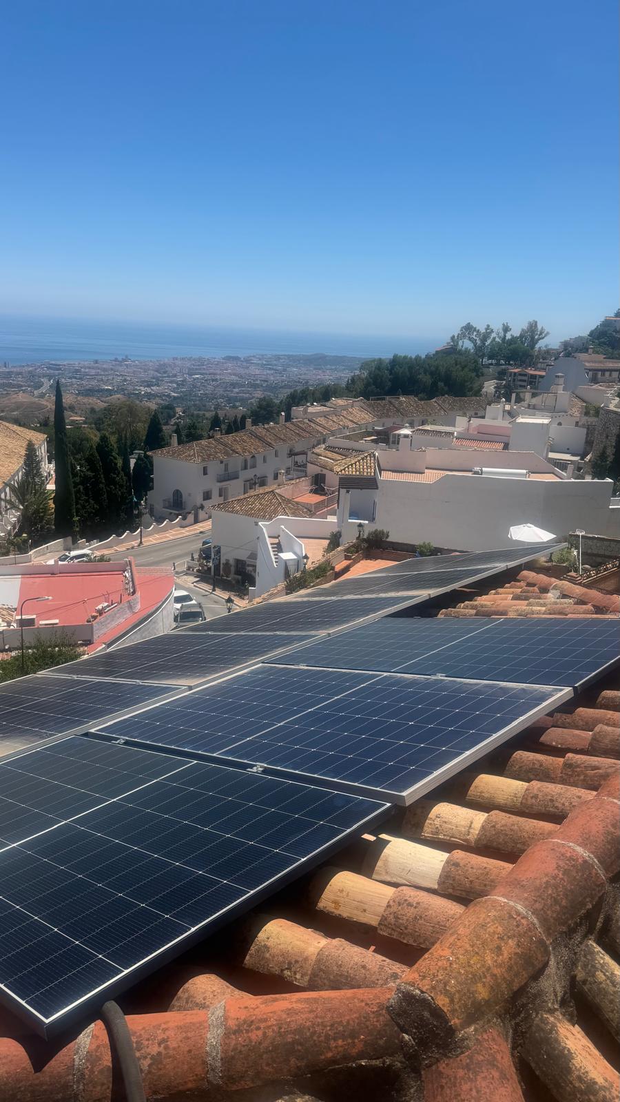 Varios paneles asegurados y avanzando — paneles montados con abrazaderas adecuadas sobre el sistema de raíles de aluminio. Vistas panorámicas a la costa de Málaga.