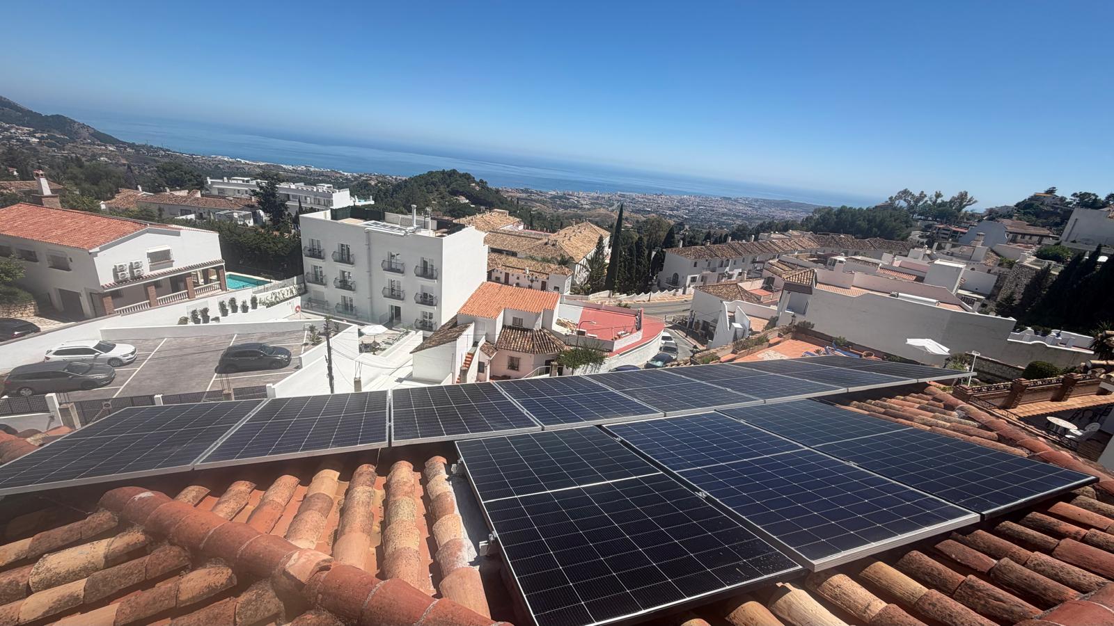 Seis paneles completamente reinstalados en el tejado de teja orientado al sur — vista amplia del Mar Mediterráneo desde esta elevada posición en el cerro de Mijas Pueblo, con Mijas Costa y la costa de Málaga visibles.
